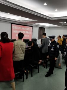 Mawei District Bureau of Justice community corrections officers fitting CO-EYE electronic monitoring wristbands on offenders during tiered classification deployment meeting