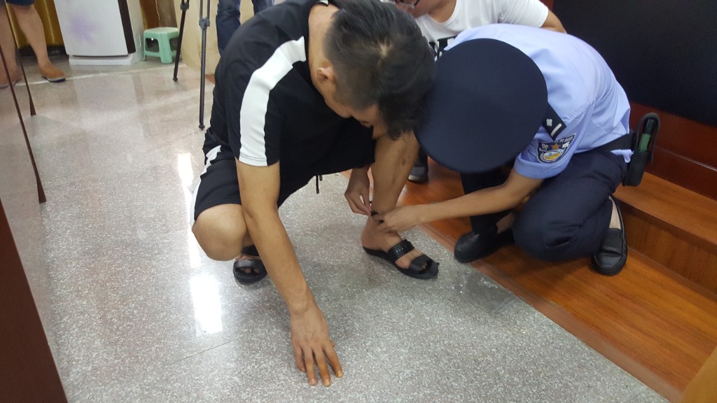Close-up of GPS ankle monitor being fitted on offender ankle during Fuqing community corrections program