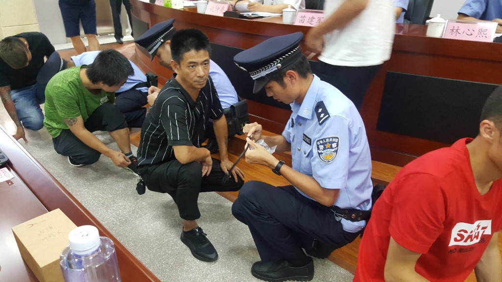 Fuqing judicial officer installing GPS ankle monitor on community corrections offender during enrollment