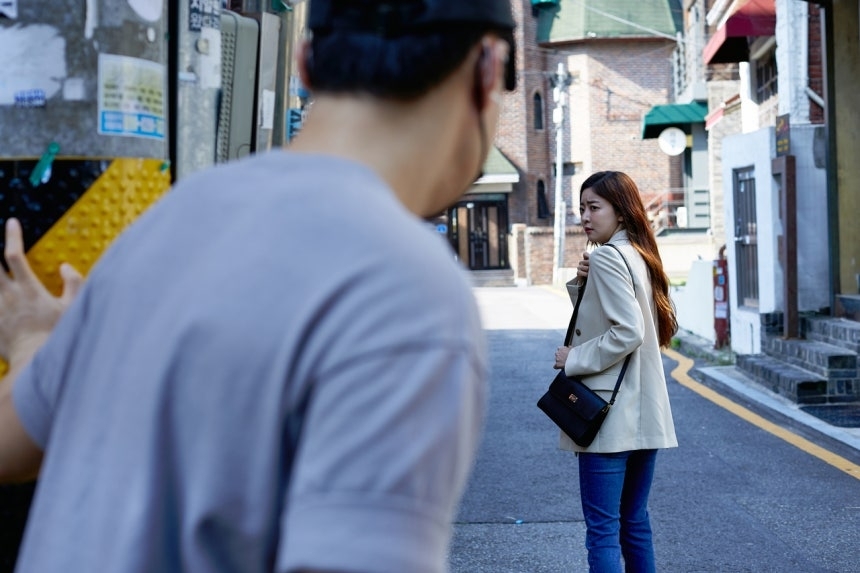A woman being followed on a street in South Korea — illustrating the stalking threat that victims face daily
